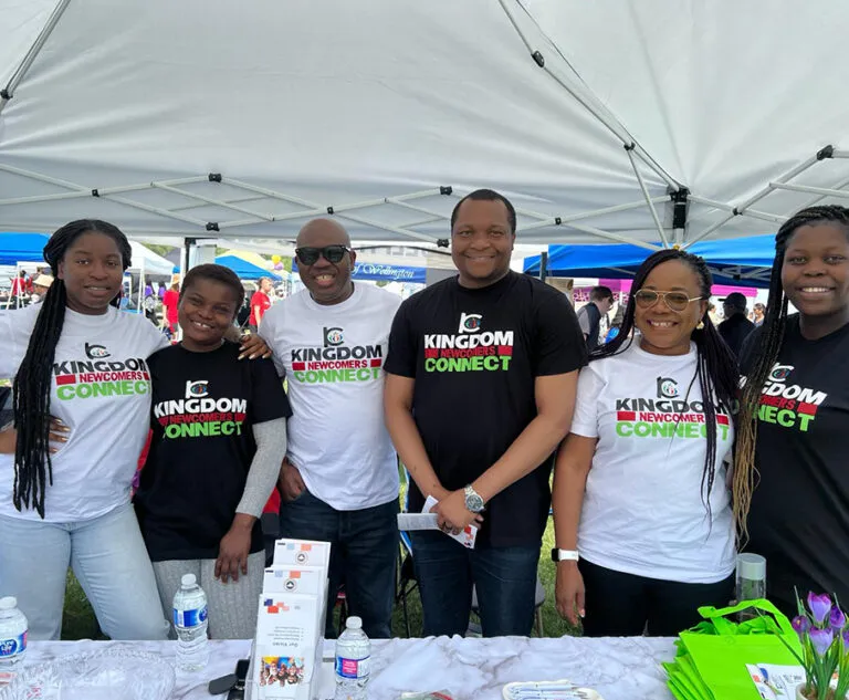 Six Kingdom Newcomers Connect members in team shirts at a tent booth, an outreach of Kingdom Stars Assembly Guelph