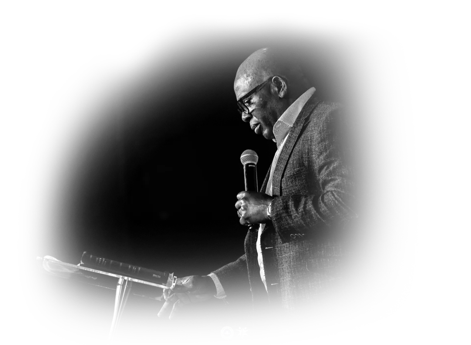 Pastor David Adeosun preaching with a microphone, black and white cutout, Kingdom Stars Assembly in Guelph