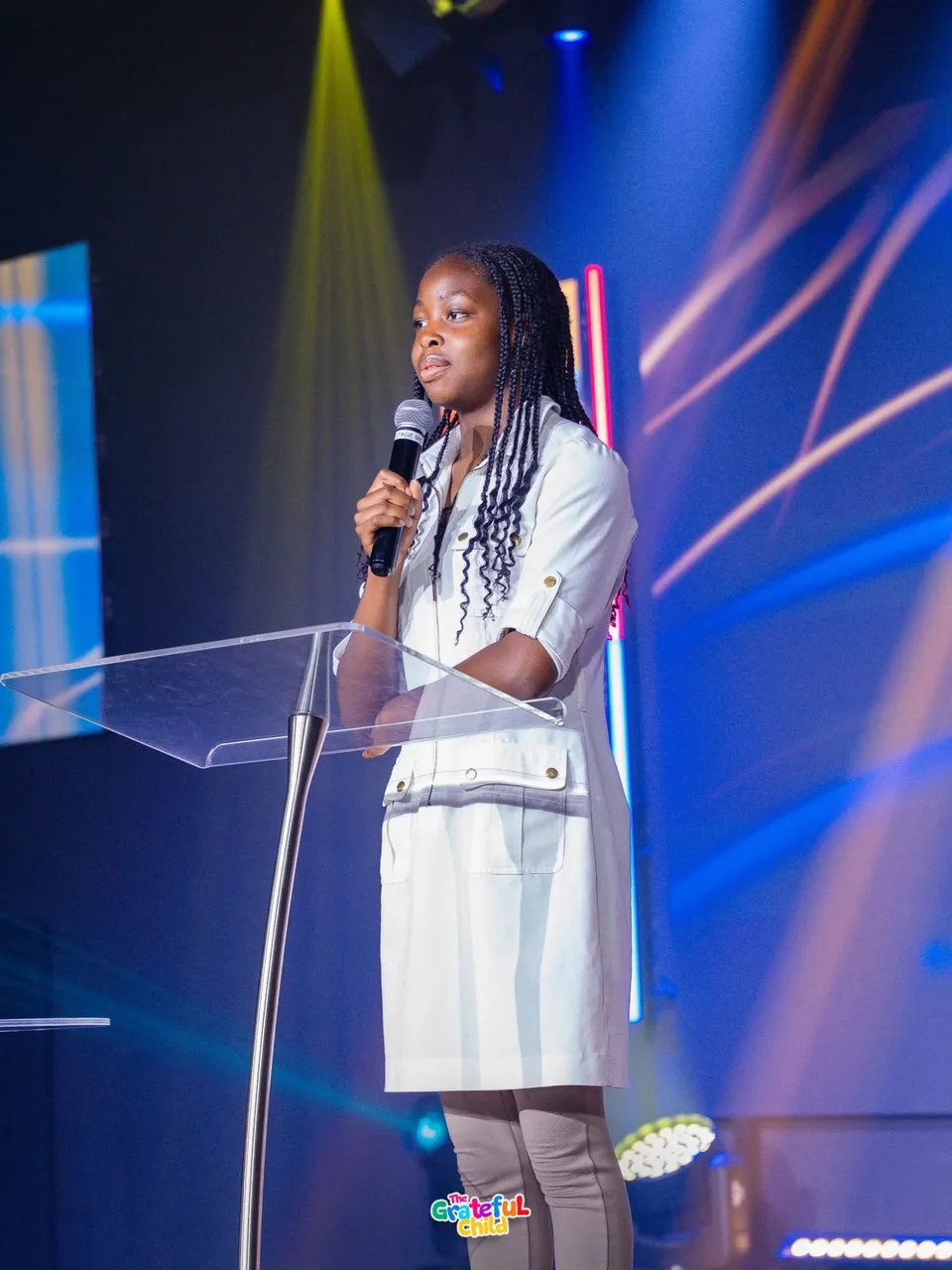 A teenage girl speaking into a microphone at the clear lectern on the Kingdom Stars Assembly stage in Guelph